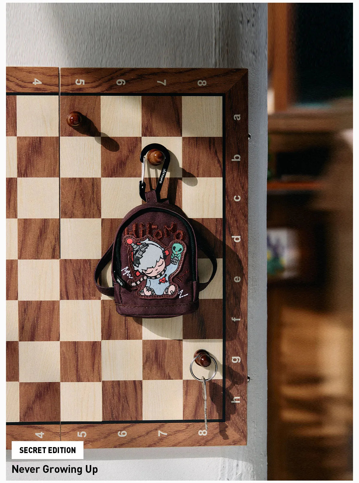 Small backpack with cartoon character design on a wooden checkered board Collectible Labubu pop mart toys Hirono