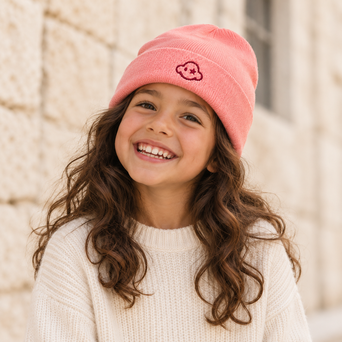 Child wearing DREAM BIG pink kids beanie — front cloud logo