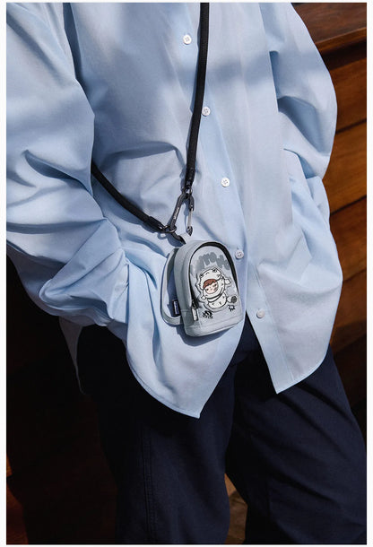 Person wearing a light blue shirt with a small gray bag featuring a cartoon character on their shoulder.  Collectible Labubu pop mart toys Hirono