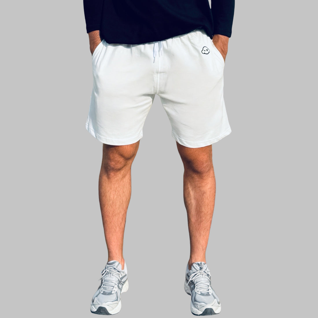 A pair of white activewear shorts with a logo on the left leg, displayed on a male model. 100% Cotton available in Dubai same day delivery best of summer and winter casual streetwear unisex men and women shorts and t-shirts available in UAE fast delivery and same day delivery available