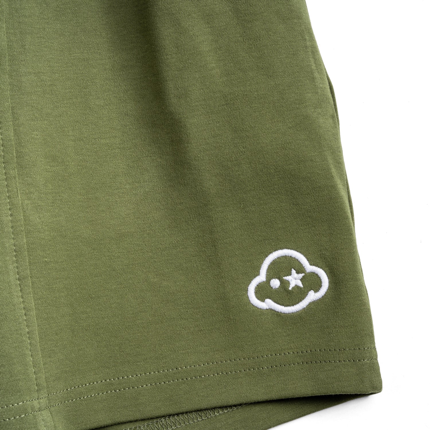 Olive green cotton shorts with a drawstring waist, featuring a small embroidered logo on the left leg and the brand name on the right leg. White cotton activewear pants with a small black logo on the left leg, featuring a relaxed fit and drawstring waist. 100% Cotton available in Dubai same day delivery best of summer and winter casual streetwear unisex men and women shorts and t-shirts available in UAE fast delivery and same day delivery available Pants joggers jogger pants